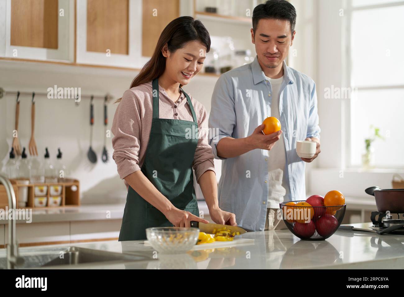 loving young asian couple chatting talking conversing in kitchen at home while preparing food Stock Photo