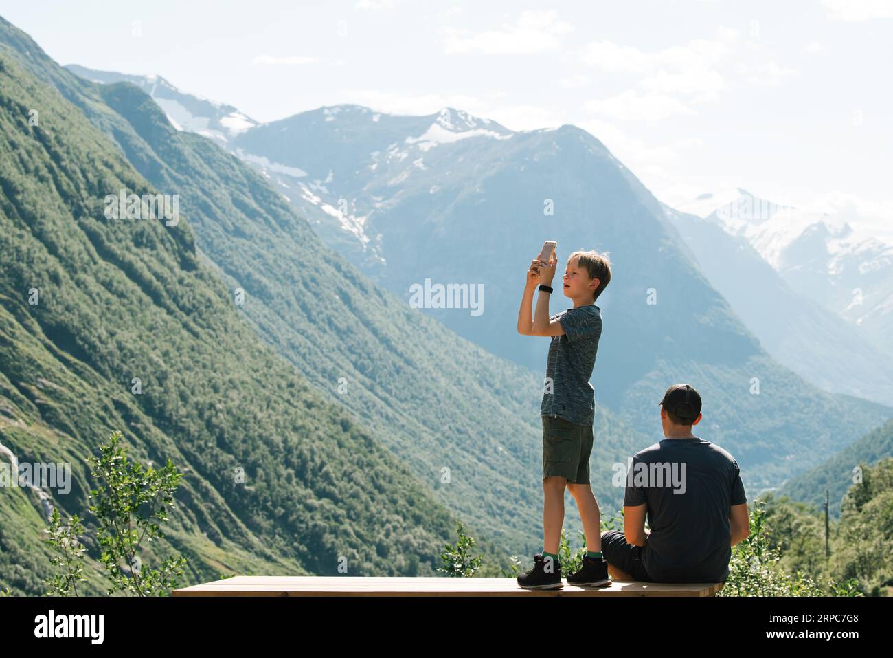 father and son taking pictures of the breathtaking view in Norway Stock Photo