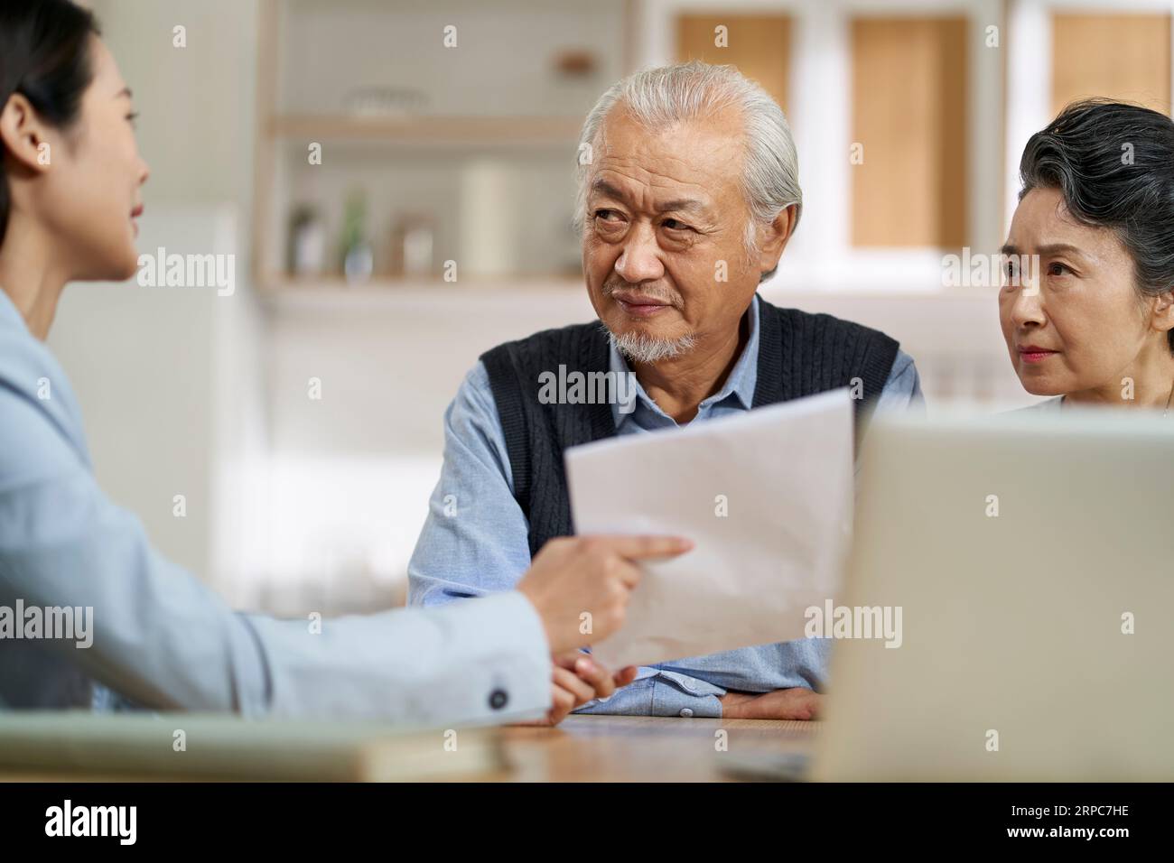 senior asian couple appears confused by and suspicious at a sales person selling financial product Stock Photo