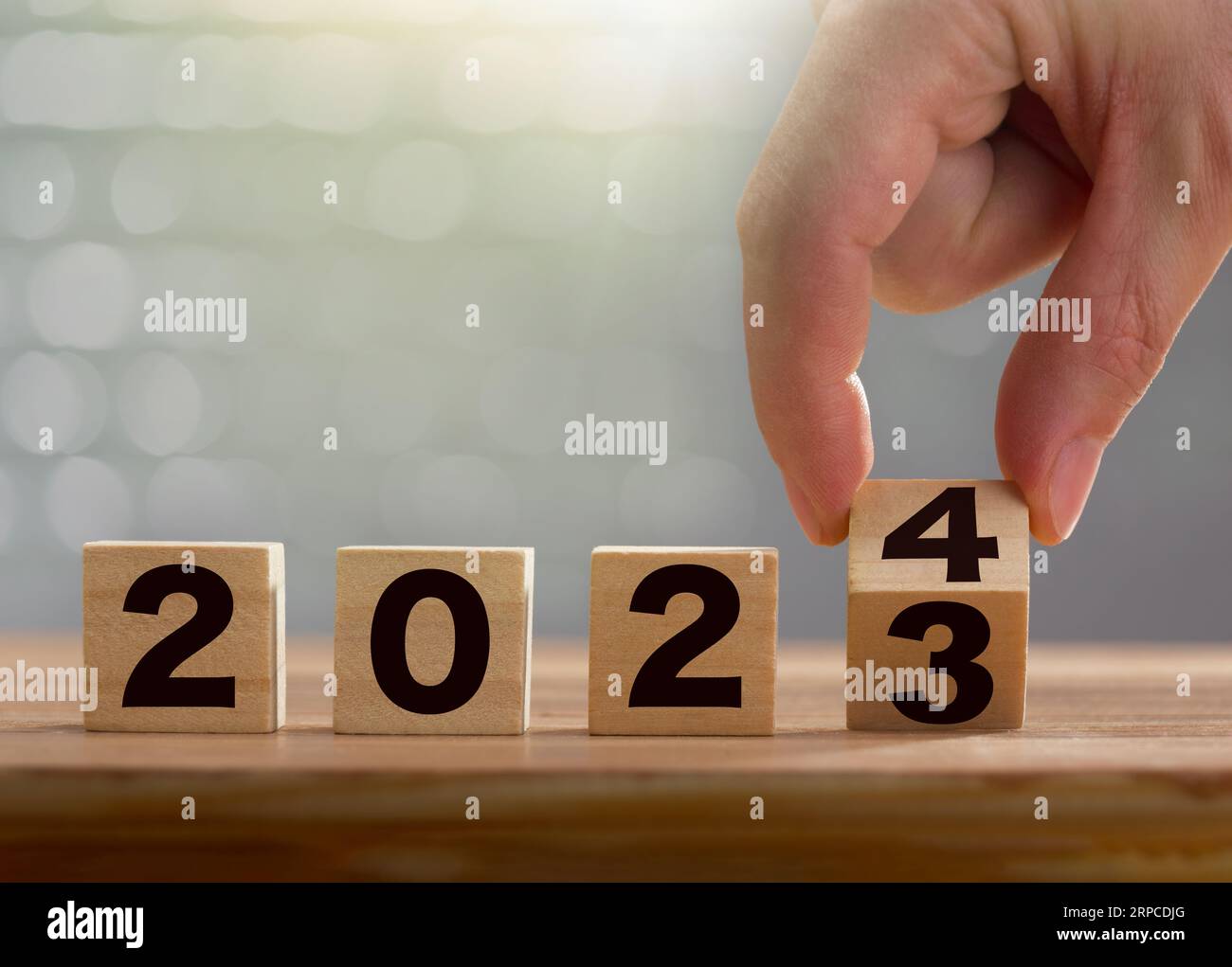 Start of the new year 2024. Business man hand flips wooden cubes with 2023 to 2024 on shiny background. Happy new year, new business, plan, goals, str Stock Photo