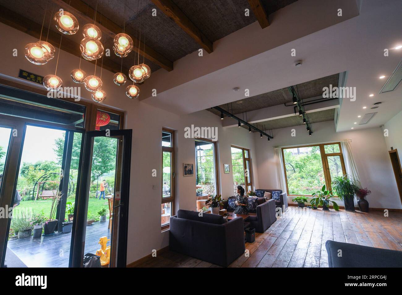 (190704) -- DEQING, July 4, 2019 -- A tourist sits in the entrance hall of a homestay lodging in Xiantan Village of Moganshan Town, Deqing County, east China s Zhejiang Province, July 4, 2019. Homestay lodgings have mushroomed in Moganshan thanks to the government s policy to encourage eco-friendly tourism which welcomes both domestic and international visitors. The local homestay business flourishes as concentrations of accommodation facilities create economies of scale, justifying itself as a path to rural revitalization. In 2018, about 2.1 million among a total of 2.6 million visitors chose Stock Photo