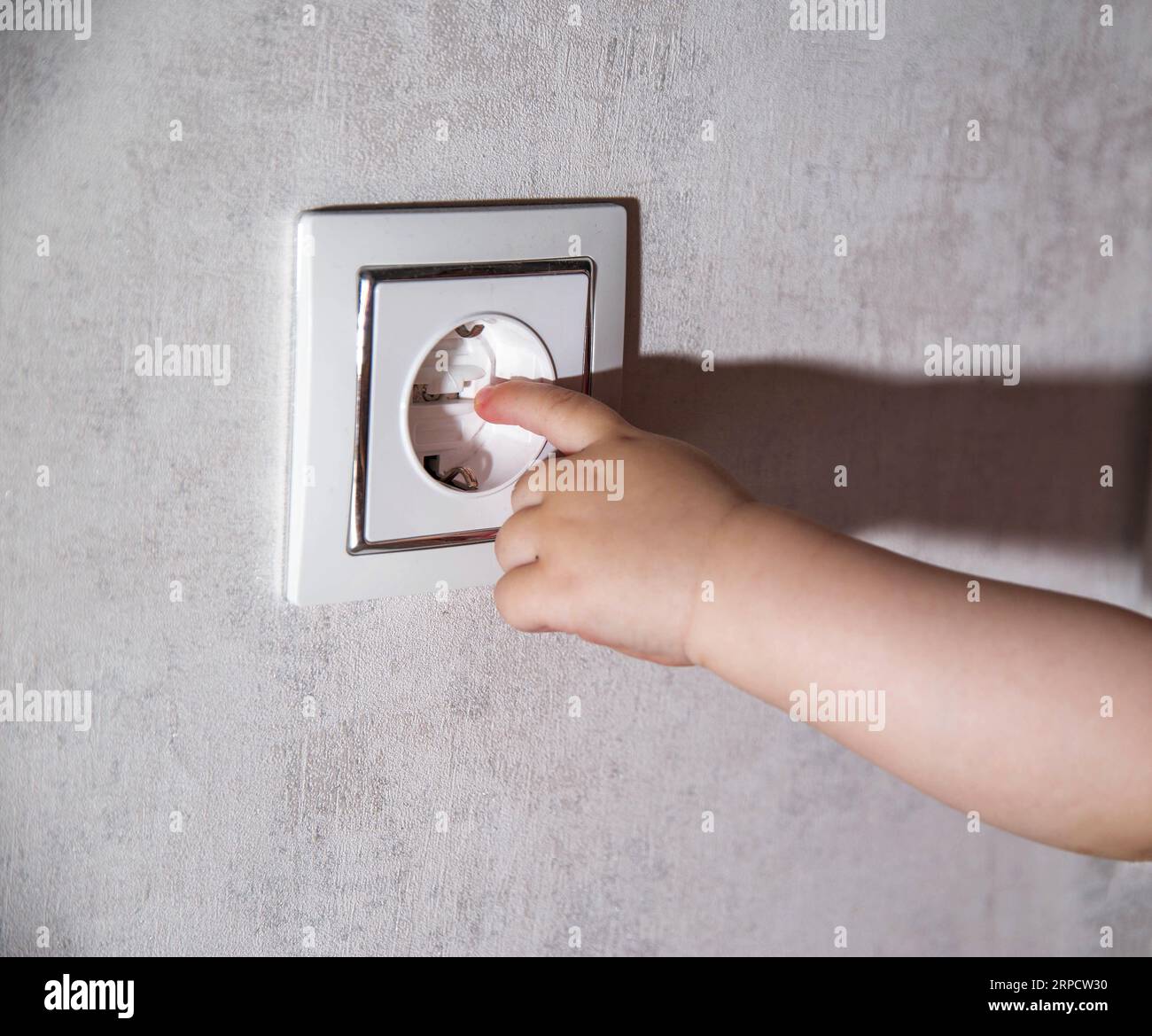 The child's hand touches the socket with a finger. Electric shock