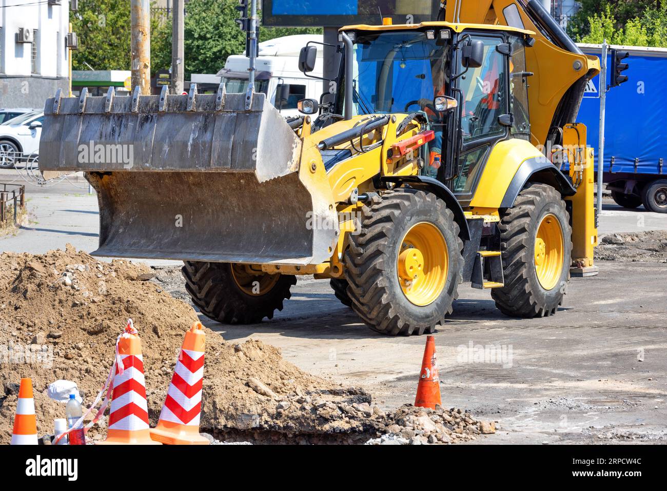 Tractor with a large hydraulic sliding bucket at a road work site on a bright sunny day. Copy space. Stock Photo