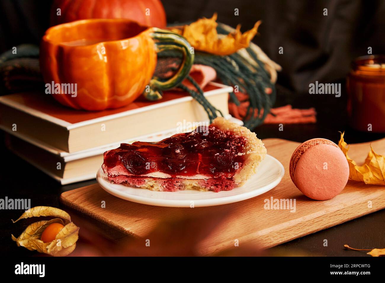 Aesthetics cozy home breakfast - cherry pie, cup of coffee in shape of pumpkin, macaroons, candle and winter cherry. Hygge home aesthetic. Stock Photo