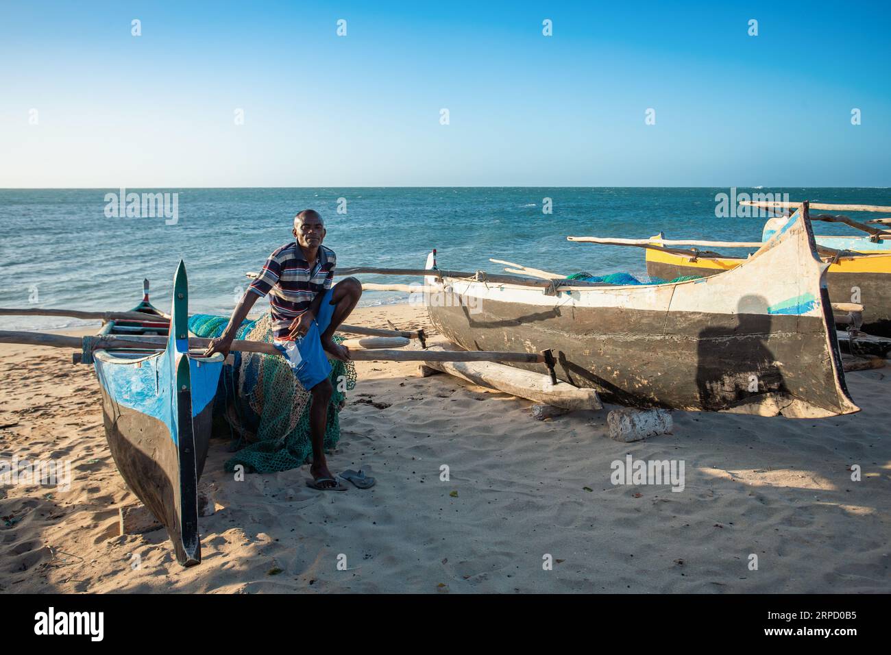ANAKAO, MADAGASCAR - NOVEMBER 21, 2022: Fishermen resting on traditional outrigger canoe in the coast of Anakao in Madagascar. Malagasy traditional bo Stock Photo