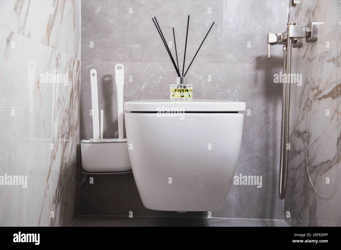 Aroma diffuser air freshener stands on a hanging toilet bowl in the