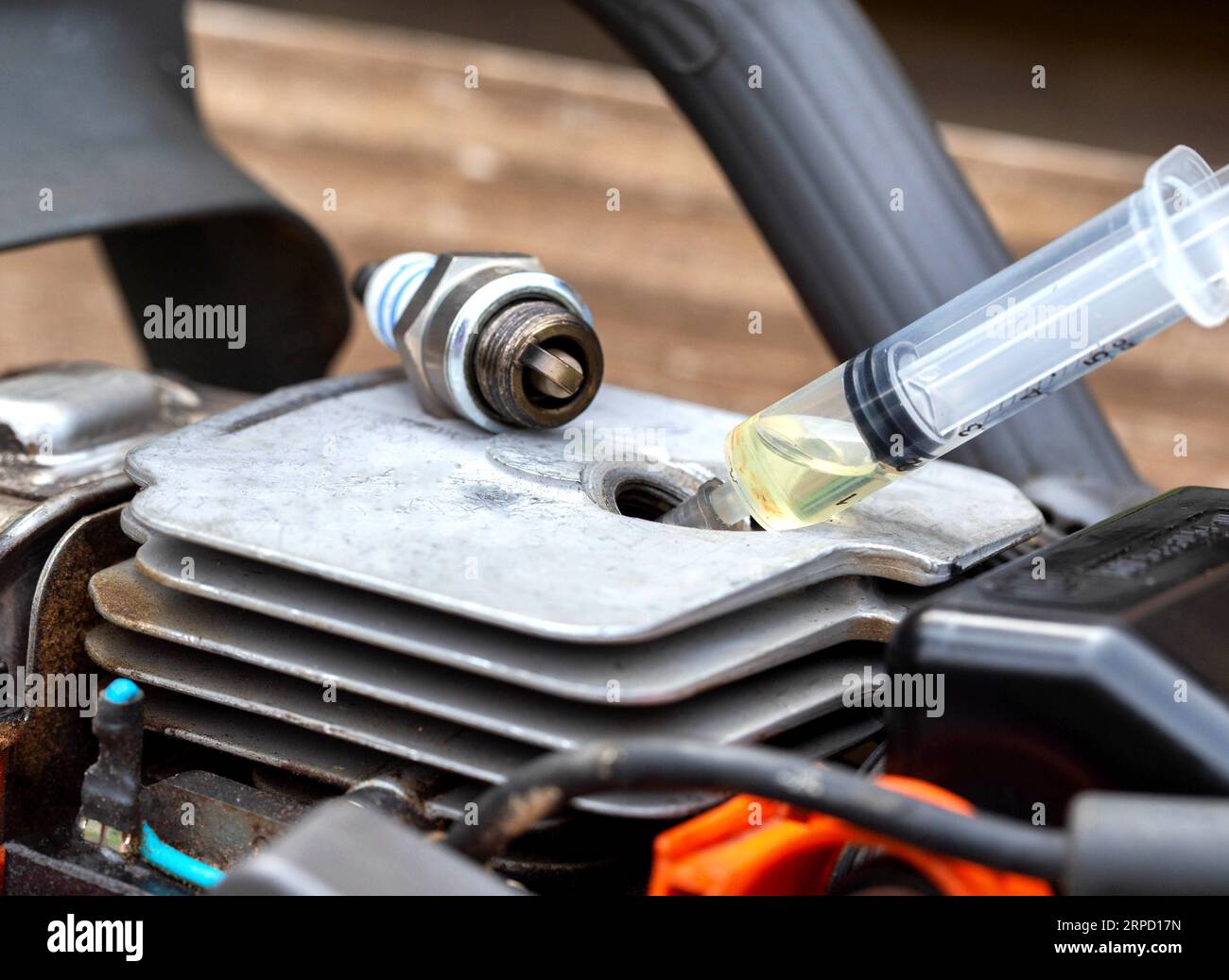 Injection of fuel from a syringe into the combustion chamber of a chainsaw. Checking the carburetor system and chainsaw ignition system. Stock Photo