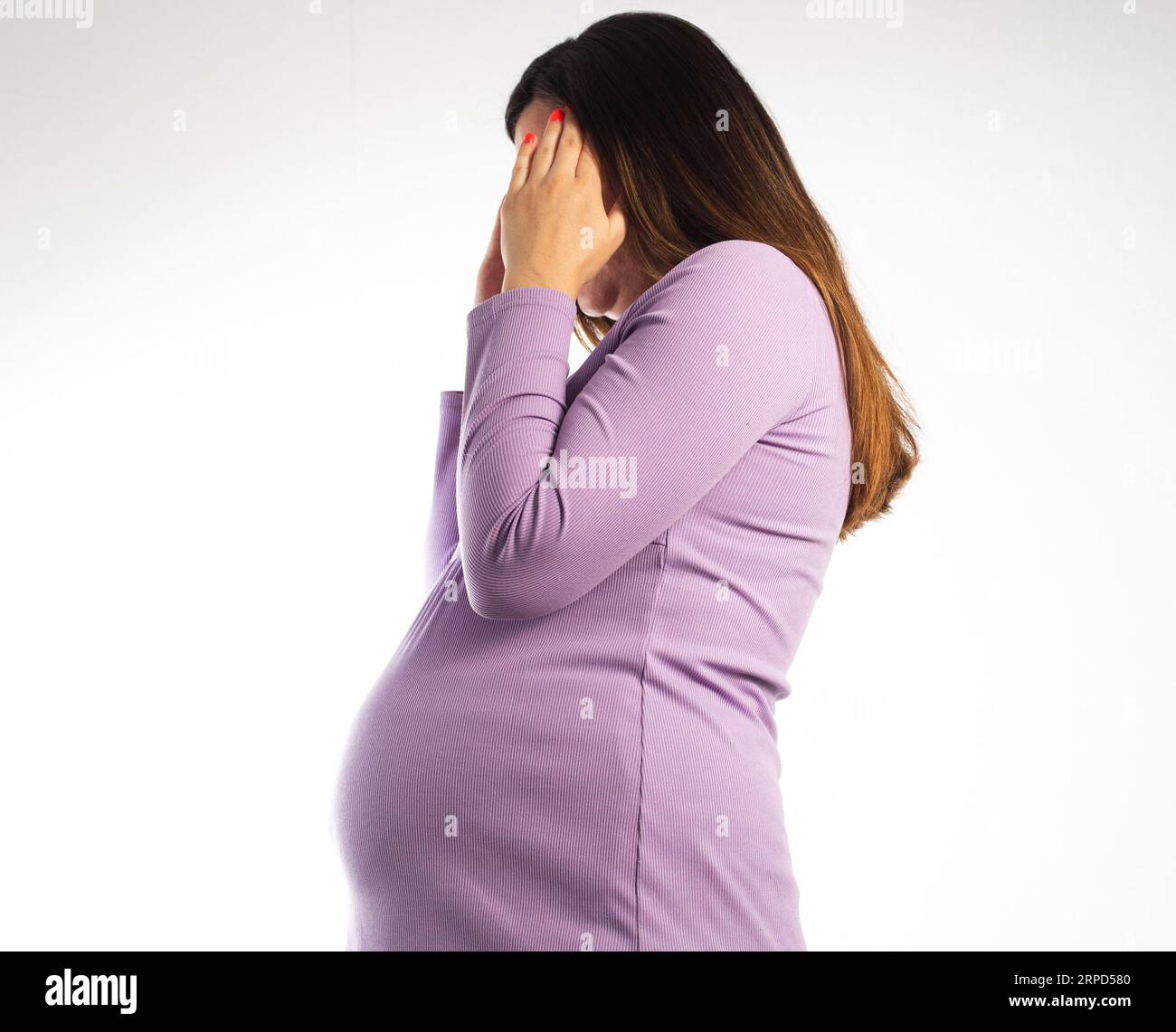 A pregnant girl in a purple blouse is holding her head. Headache in pregnancy. Elevated levels