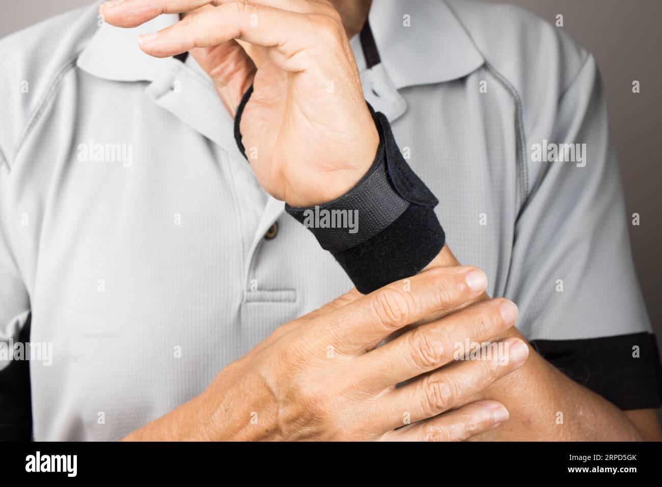 A closeup of a man wearing a wrist brace on his left hand and wrist for