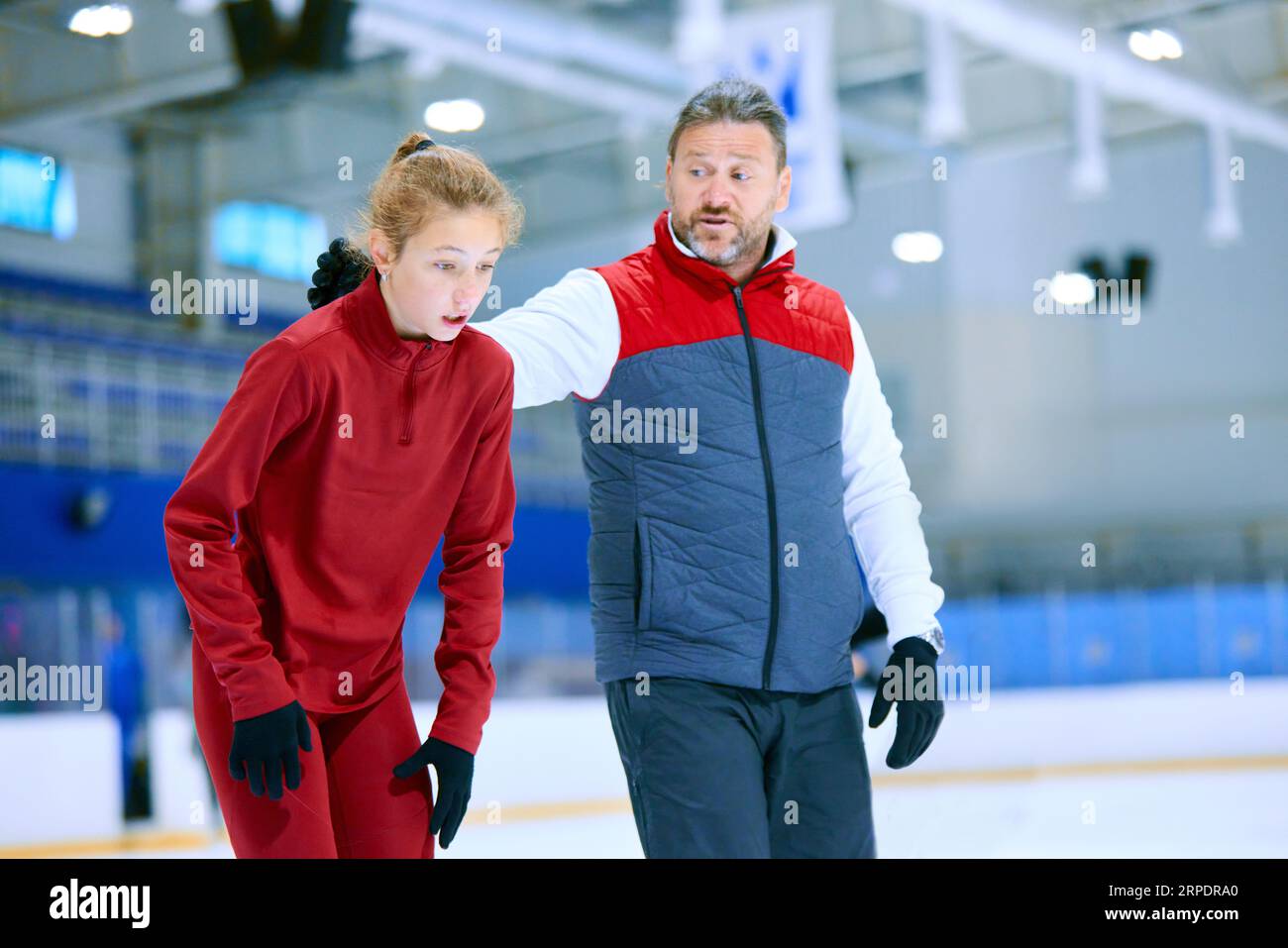 Coaching and assistance. Man, professional coach teaching girl to skate