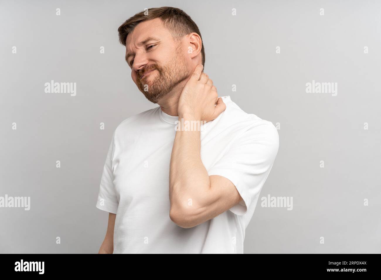 Unhealthy man suffering painful neck ache after sports exercise. Back pain and hernia, sedentary.  Stock Photo