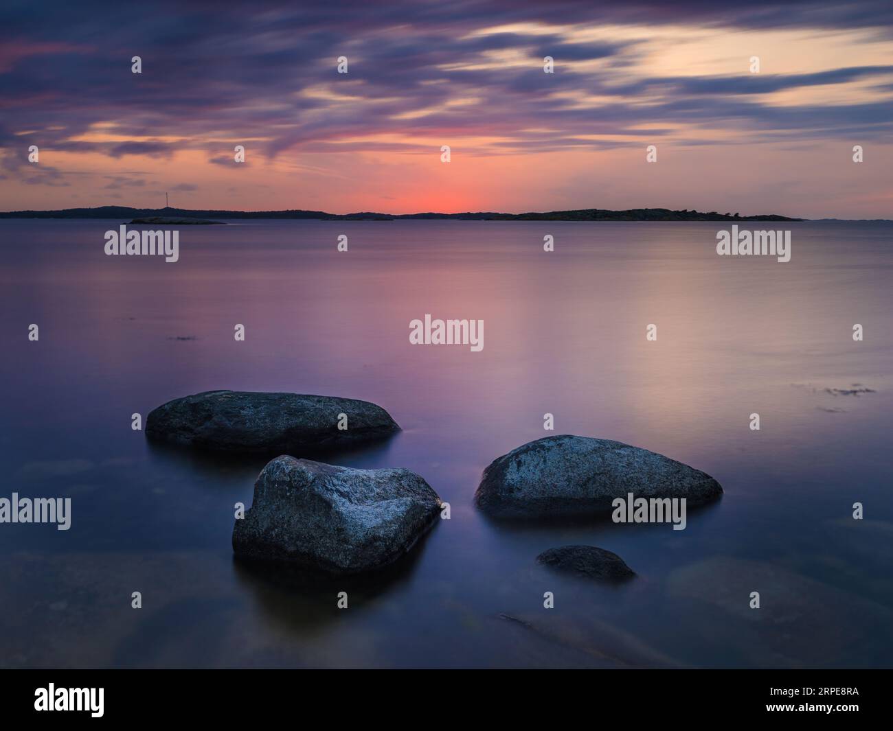 Nature's beauty at Sweden's coast: tranquil beach, sunset, ocean reflection, rocky shoreline. Stock Photo