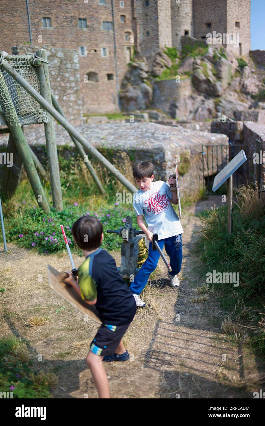 Two young caucasian boys pretend to fight with wooden swords and shields during a visit to an historic castle Stock Photo