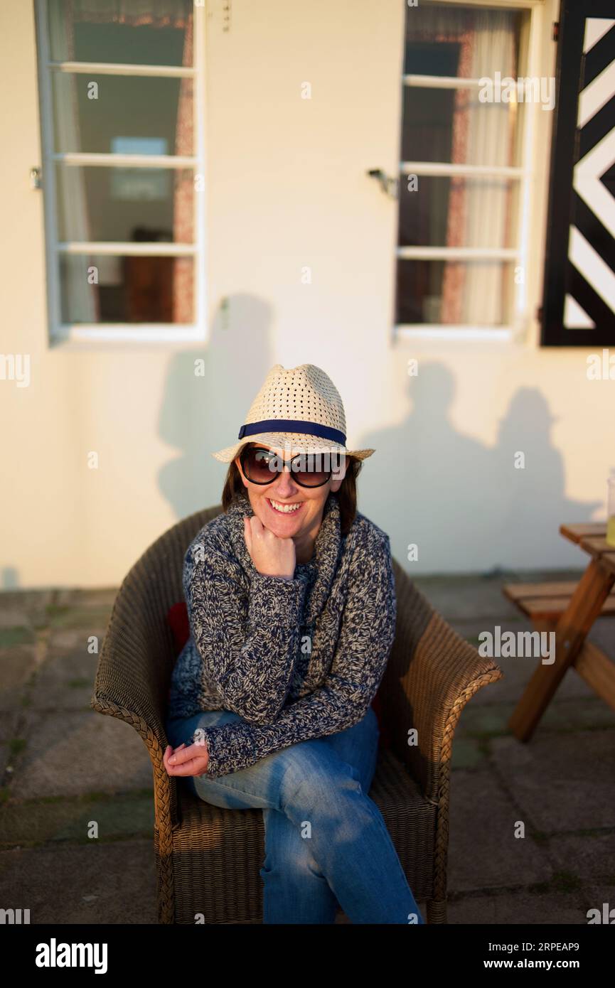 Portrait of caucasian young woman wearing a white hat smiling in the late summers evening. Stock Photo