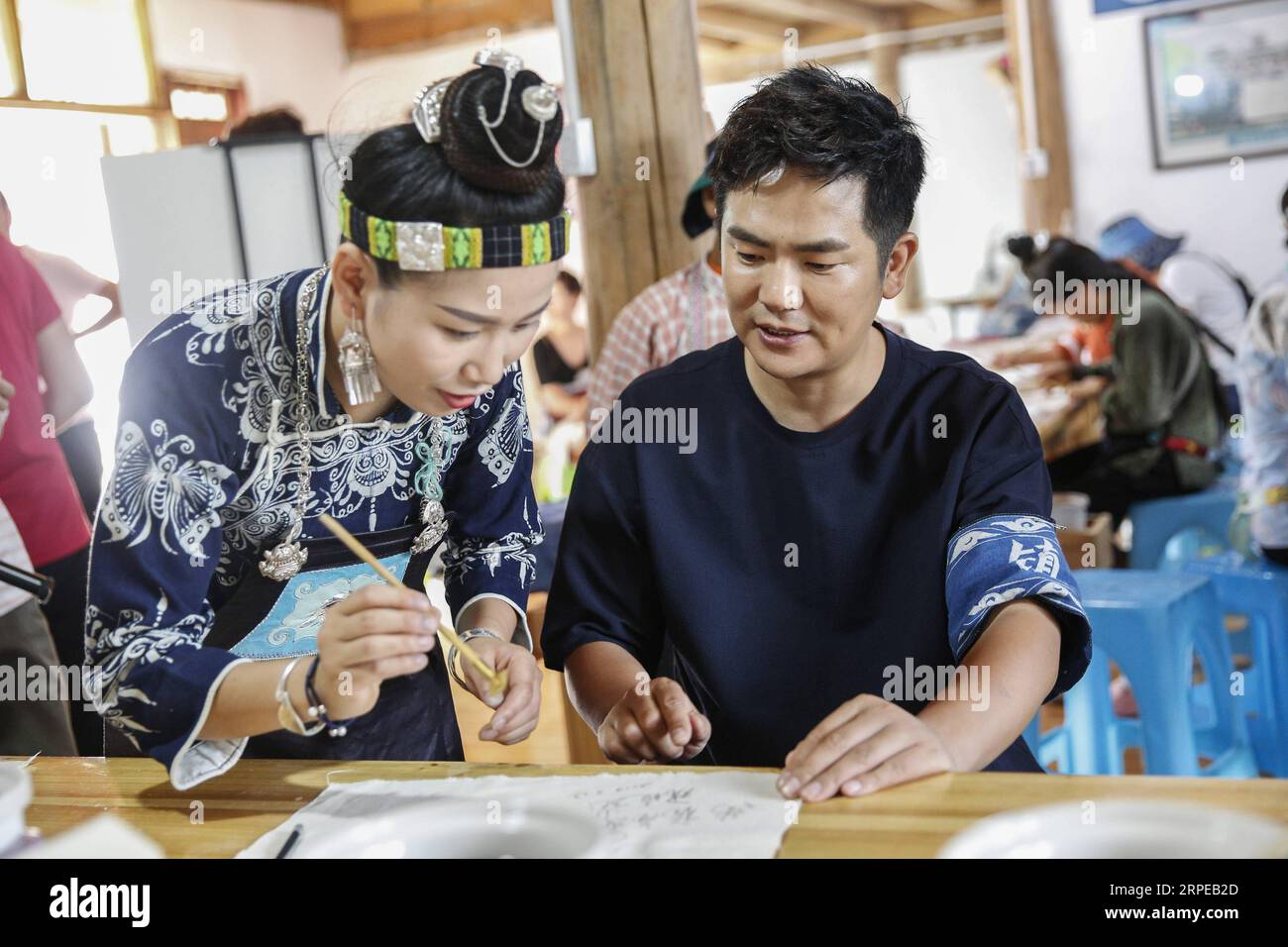 (190823) -- DANZHAI, Aug. 23, 2019 -- Actor Zhang Xiaolong (R), also an ambassador for Mom Handworks , tries batik at a batik craft cooperative of Mom Handworks in Danzhai County, southwest China s Guizhou Province, Aug. 23, 2019. A handicraft cooperative and a batik craft cooperative of Mom Handworks , a public welfare project initiated by China Women s Development Foundation (CWDF), were put into operation in Guizhou s Taijiang and Danzhai respectively. The landing of two cooperatives explores a new mode on poverty alleviation, combining local government, non-profit organizations and cultura Stock Photo