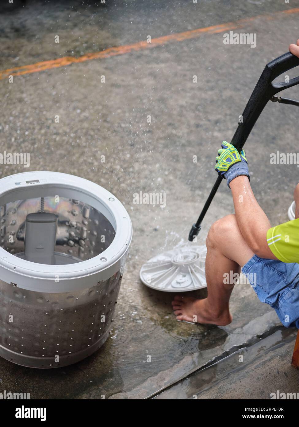 Hands of repairman using  Water sprayer machine after repairing or removing it to clean the drum,repair of household electrical appliances or cleaning Stock Photo