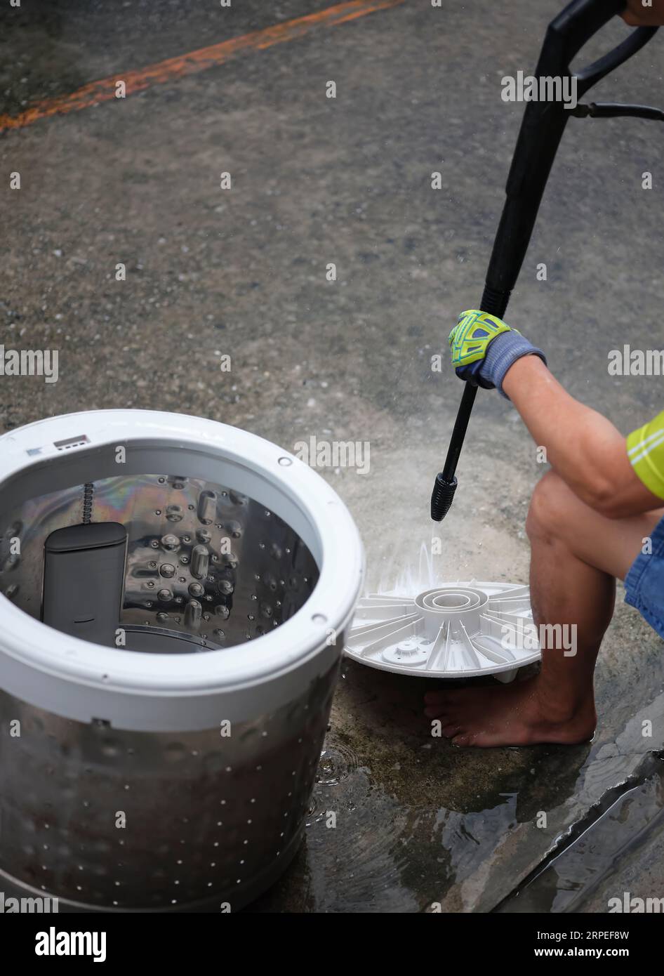 Hands of repairman using  Water sprayer machine after repairing or removing it to clean the drum,repair of household electrical appliances or cleaning Stock Photo