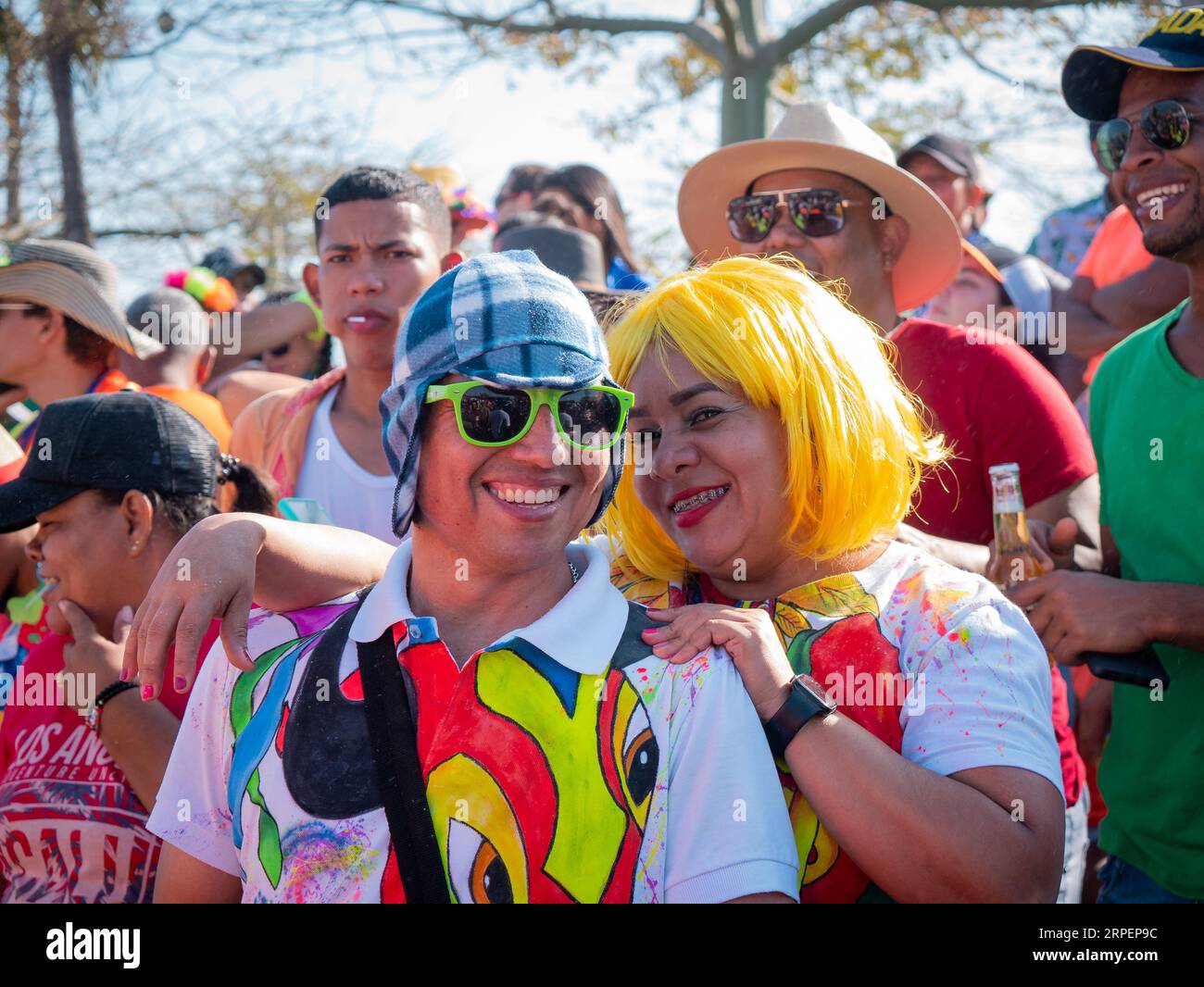 Barranquilla, Atlantico, Colombia - February 18 2023: Colombian Man Wearing a Colorful T-shirt, Glasses  and Cap Stands next to a Woman Wearing a Yell Stock Photo