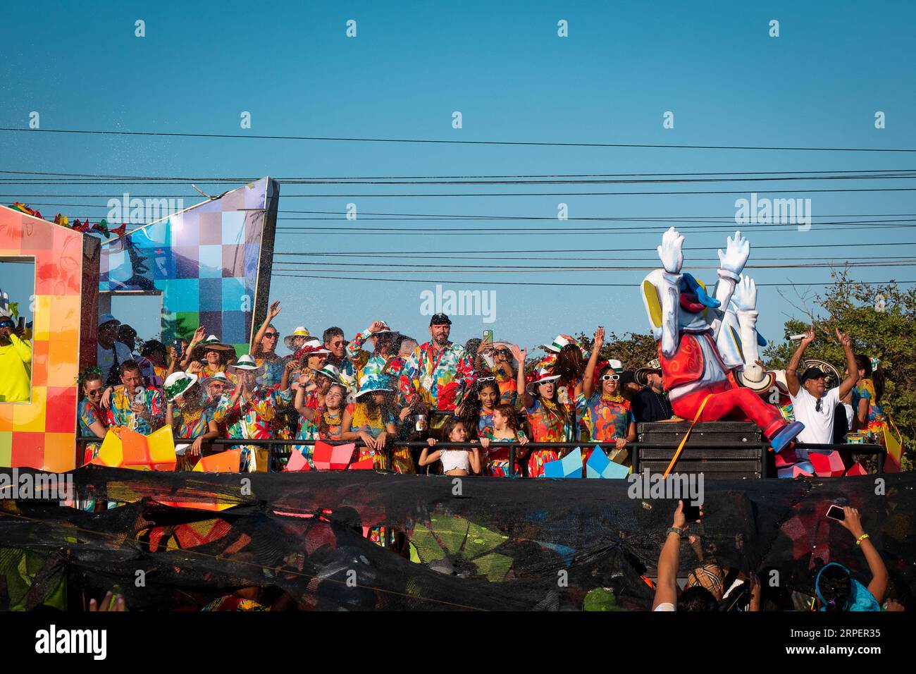 Barranquilla, Atlantico, Colombia - February 18 2023: Men and Women Dressed in Colorful Flower Shirts Stand on a Float in the Carnival Parade and Wave Stock Photo