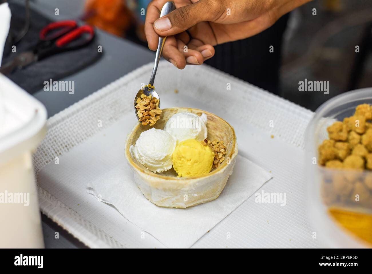 Hand holding coconut and mango ice cream in coconut shell in Jalan Alor street food market in Kuala Lumpur Stock Photo