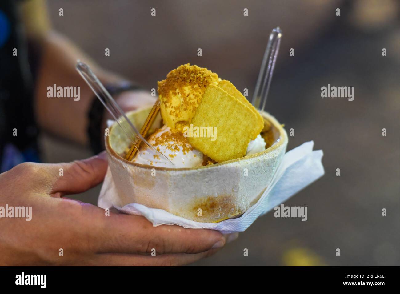 Hand holding coconut and mango ice cream in coconut shell in Jalan Alor street food market in Kuala Lumpur Stock Photo