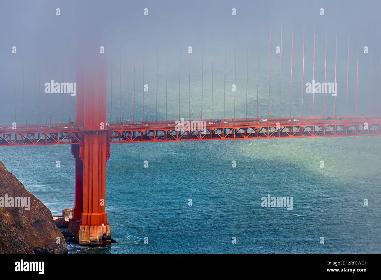 The Golden Gate Bridge stands against a backdrop of billowing clouds and the vast ocean below Stock Photo