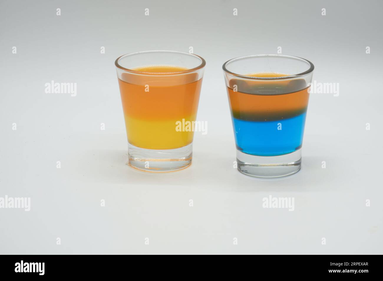 Two Shot glasses, One with Orange and Lemon Jelly and the other Blue Berry and Orange Jelly Isolated on a white background Stock Photo