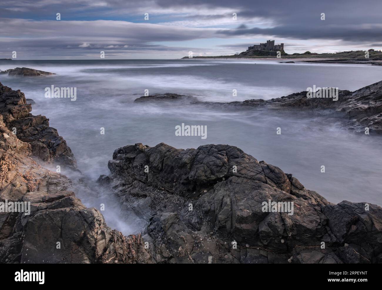 Incoming tide at Bamburgh with Bamburgh Castle in the background (November) Bamburgh, Northumberland, UK Stock Photo