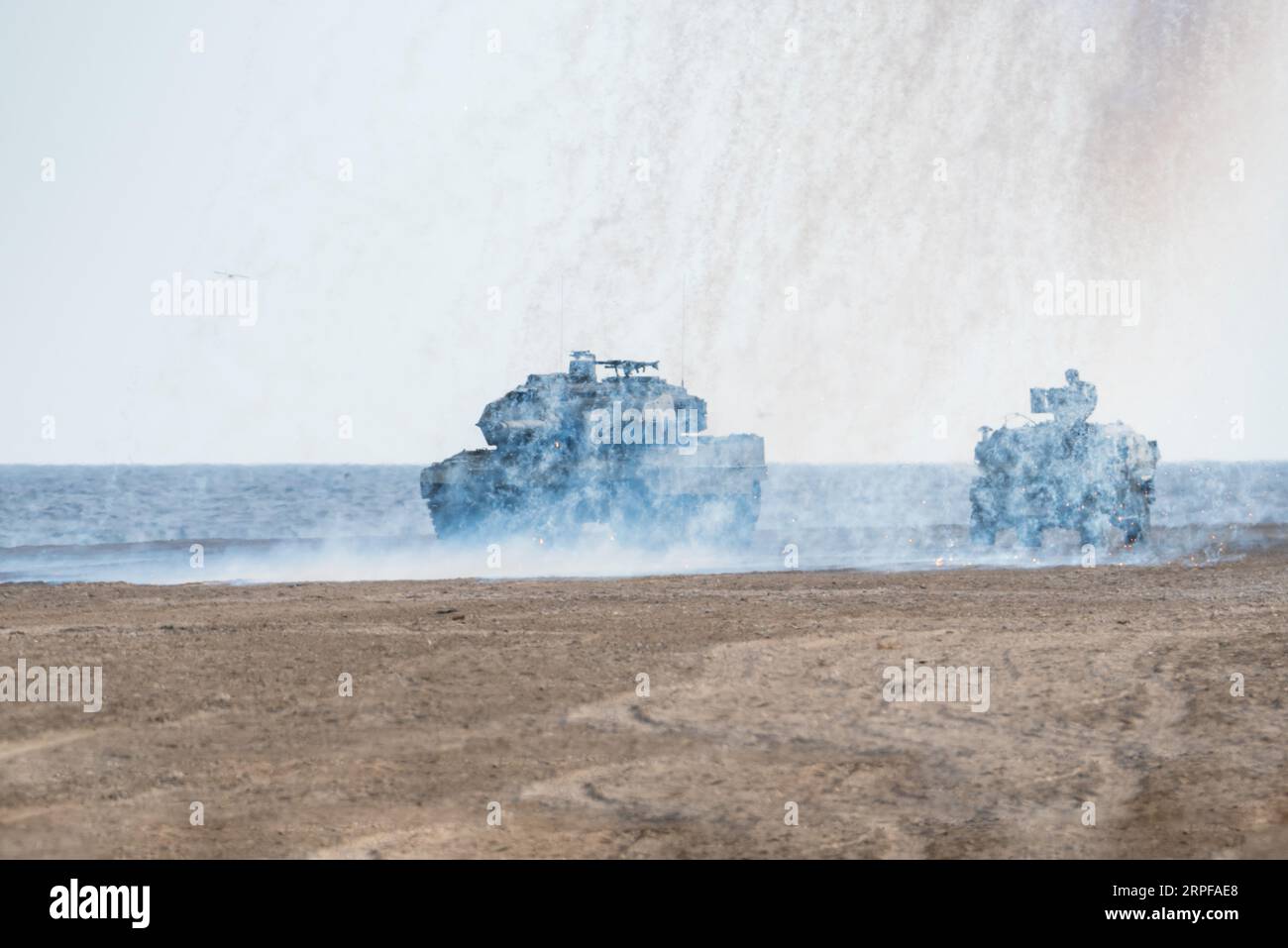 Battle tanks under a screen of smoke at the Armed Forces Day exhibition on Motril beach. Stock Photo