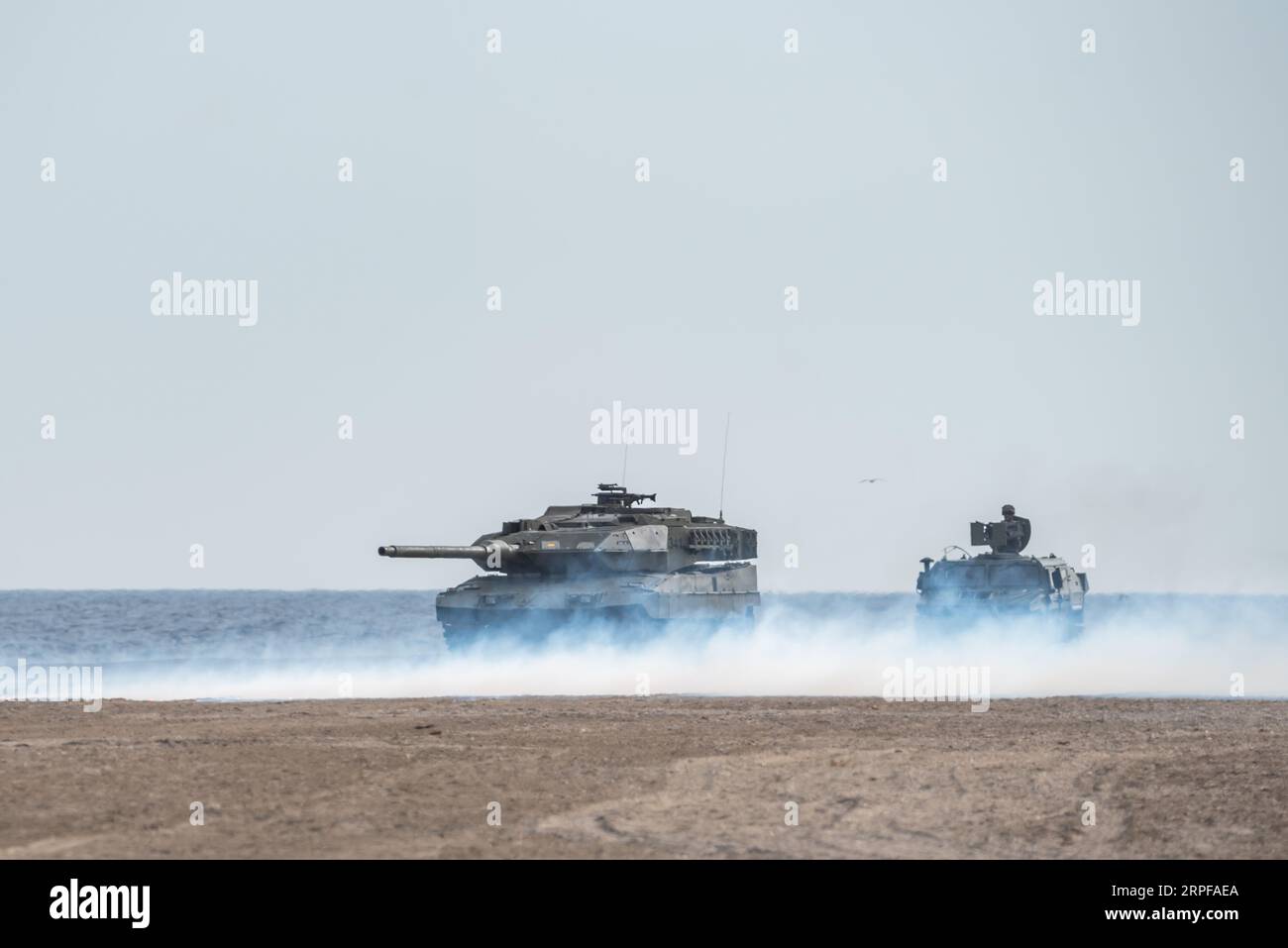 Battle tanks under a screen of smoke at the Armed Forces Day exhibition on Motril beach. Stock Photo