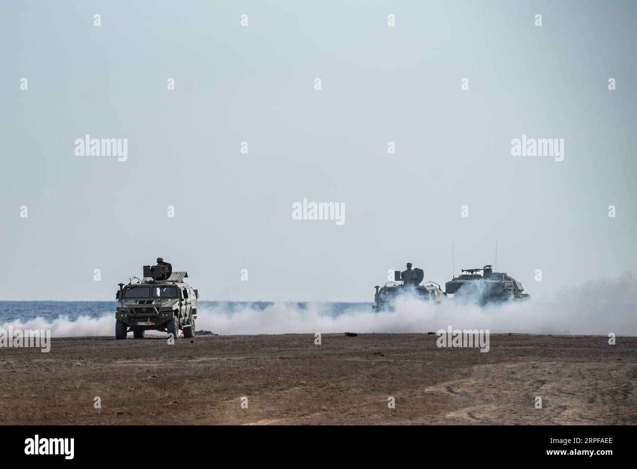 Battle tank, assault vehicles and soldiers under a smoke screen at the Armed Forces Day exhibition on Motril beach. Stock Photo