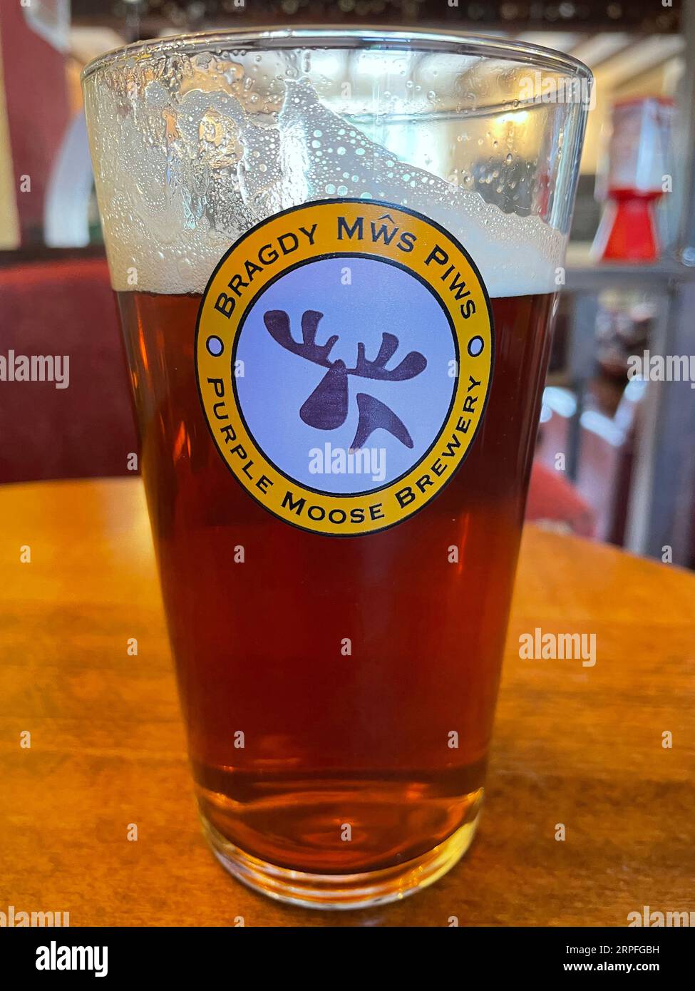 Pint of beer in the middle of being drunk. Purple Moose Brewery, Bragdy Mws Piws. Stock Photo