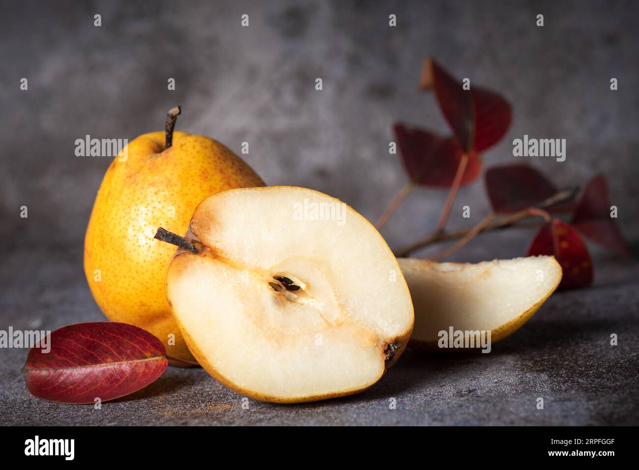 Yellow, large, organic pear cut in half, on gray background Stock Photo