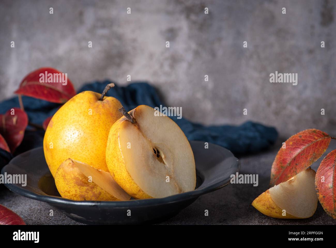 Yellow, large, organic pear cut in half, in a nice deep bowl and a gray background Stock Photo