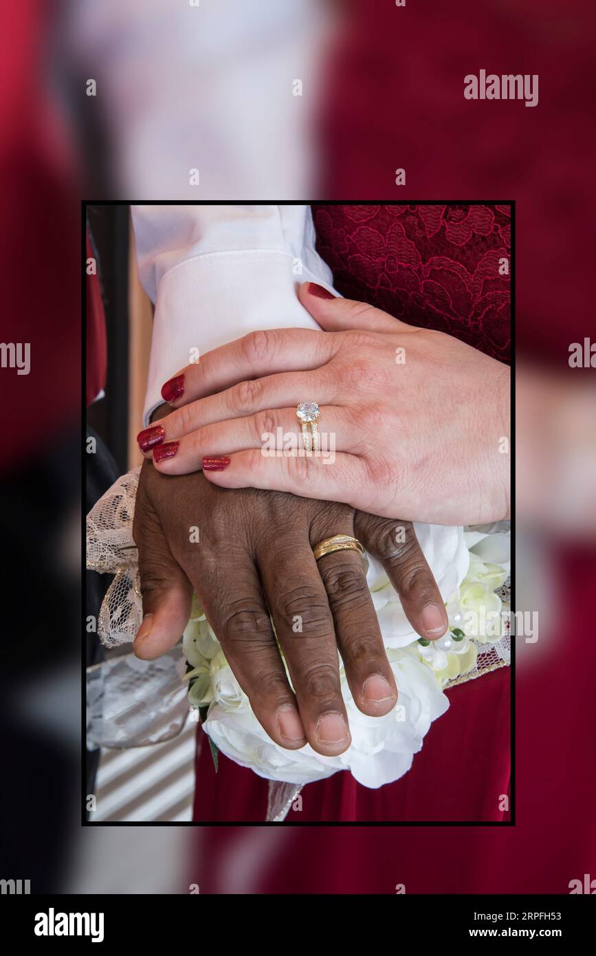 Beautiful portrait of the rings and hands of interracial couple on their wedding day. Stock Photo