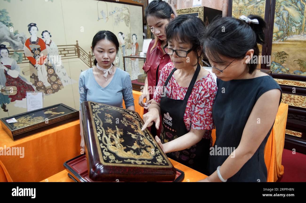 190924 -- BEIJING, Sept. 24, 2019 -- Hu Xin 2nd R explains a gold inlaid lacquer work at Beijing Gold Lacquer Inlaid Co., Ltd. in Beijing, capital of China, Sept. 19, 2019. Gold inlaid lacquer, an integral part of painted and inlaid lacquer, is among the eight Beijing-style handicrafts. Gold inlaid lacquer ware combines the intricate skills of carving, filling, whetting, inlaying and painting. It features a gold lacquered surface inlaid with various gems and other exotic materials. Hu Xin, a 62-year-old senior arts and crafts master of Beijing, has been dedicated to designing and creating lacq Stock Photo