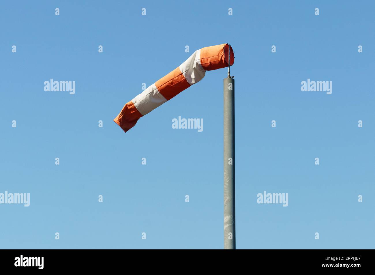 A red and white wind cone indicating the direction and strength of the wind. Strong wind, cone in horizontal position. Stock Photo