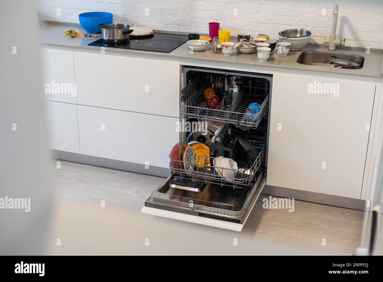 White kitchen counter and opened empty dishwasher wit grey