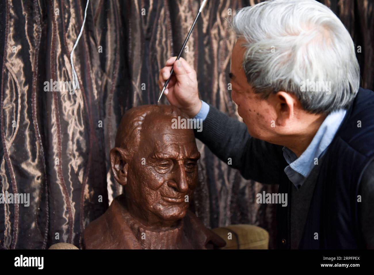 190929 -- WELLINGTON, Sept. 29, 2019 -- Deng Bangzhen, a painter and one of Rewi Alley s adopted sons, colors a statue featuring Rewi Alley in Auckland, New Zealand, Aug. 30, 2019. People from both New Zealand and China still very often talk about Rewi Alley, a New Zealand-born writer, social reformer and educator, even 32 years after his death in Beijing. An old friend of the Chinese people, Rewi Alley spent 60 years living and working in China. He made important contributions to the Chinese people s fight against the fascist invasion, the economic development of the new China, and the friend Stock Photo