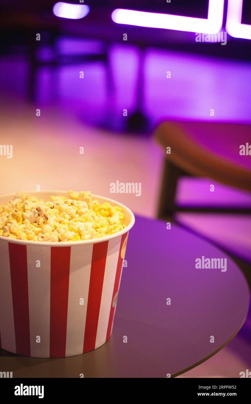 Popcorn box in neon lights. Movie theatre popcorn background