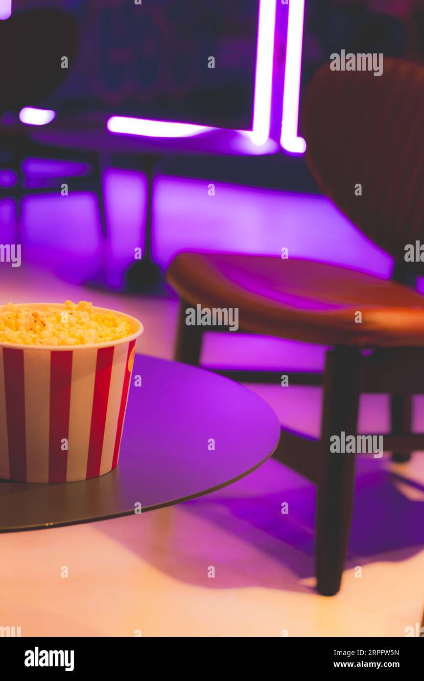 Popcorn box in neon lights. Movie theatre popcorn background