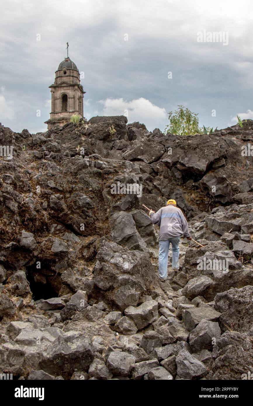 Man walking through volcanic rocks on a ruined building. Stock Photo