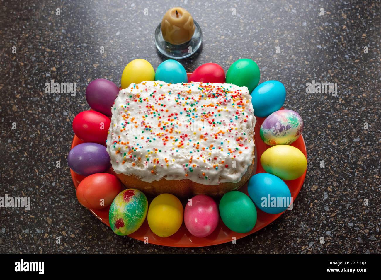 festive Easter cake and painted multi-colored eggs lying around, top view. Stock Photo