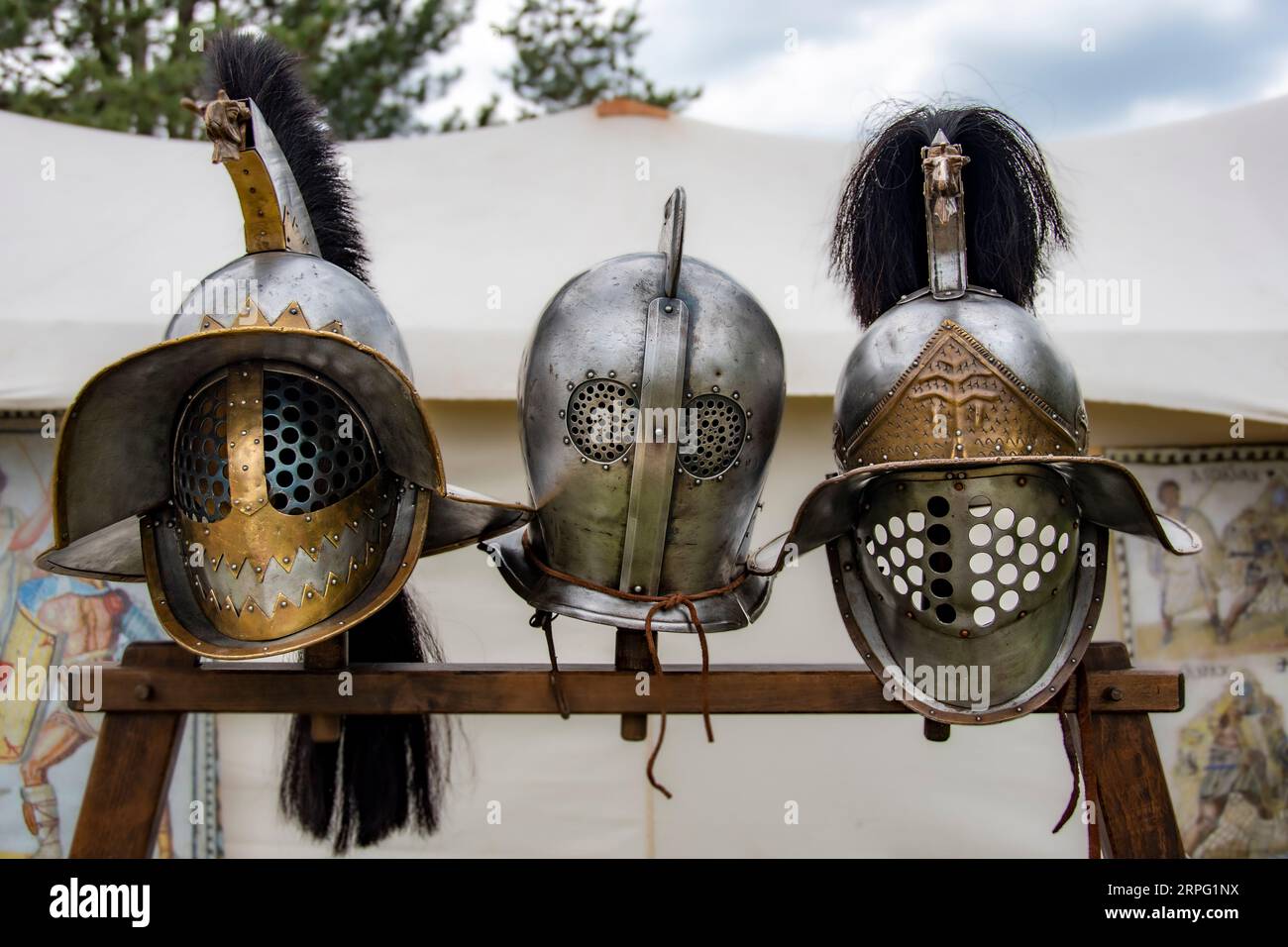3 ancient roman gladiator helmets on a stand in front of a tent Stock Photo