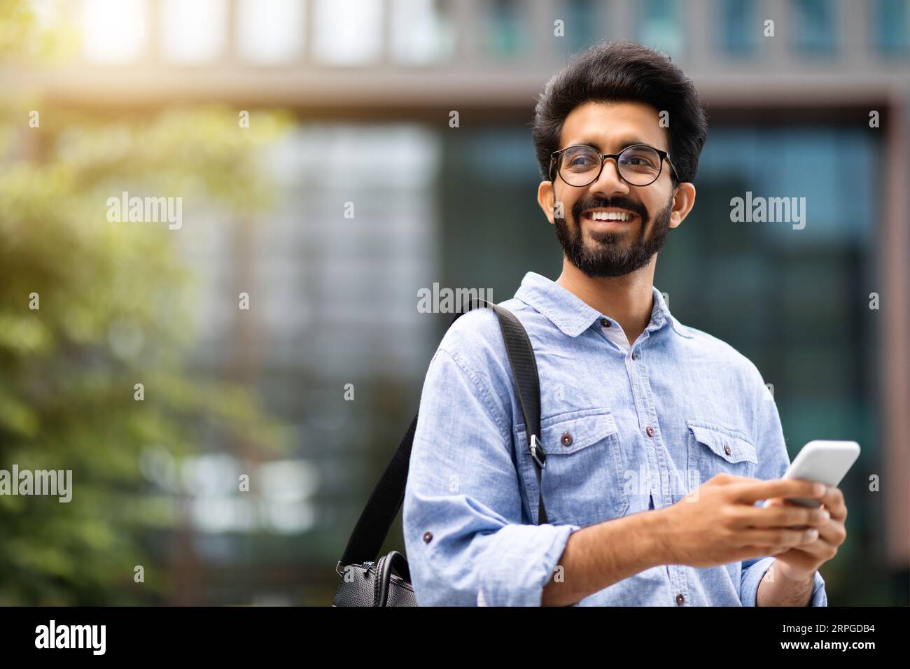 Cheerful eastern millennial man IT manager using cell phone Stock Photo
