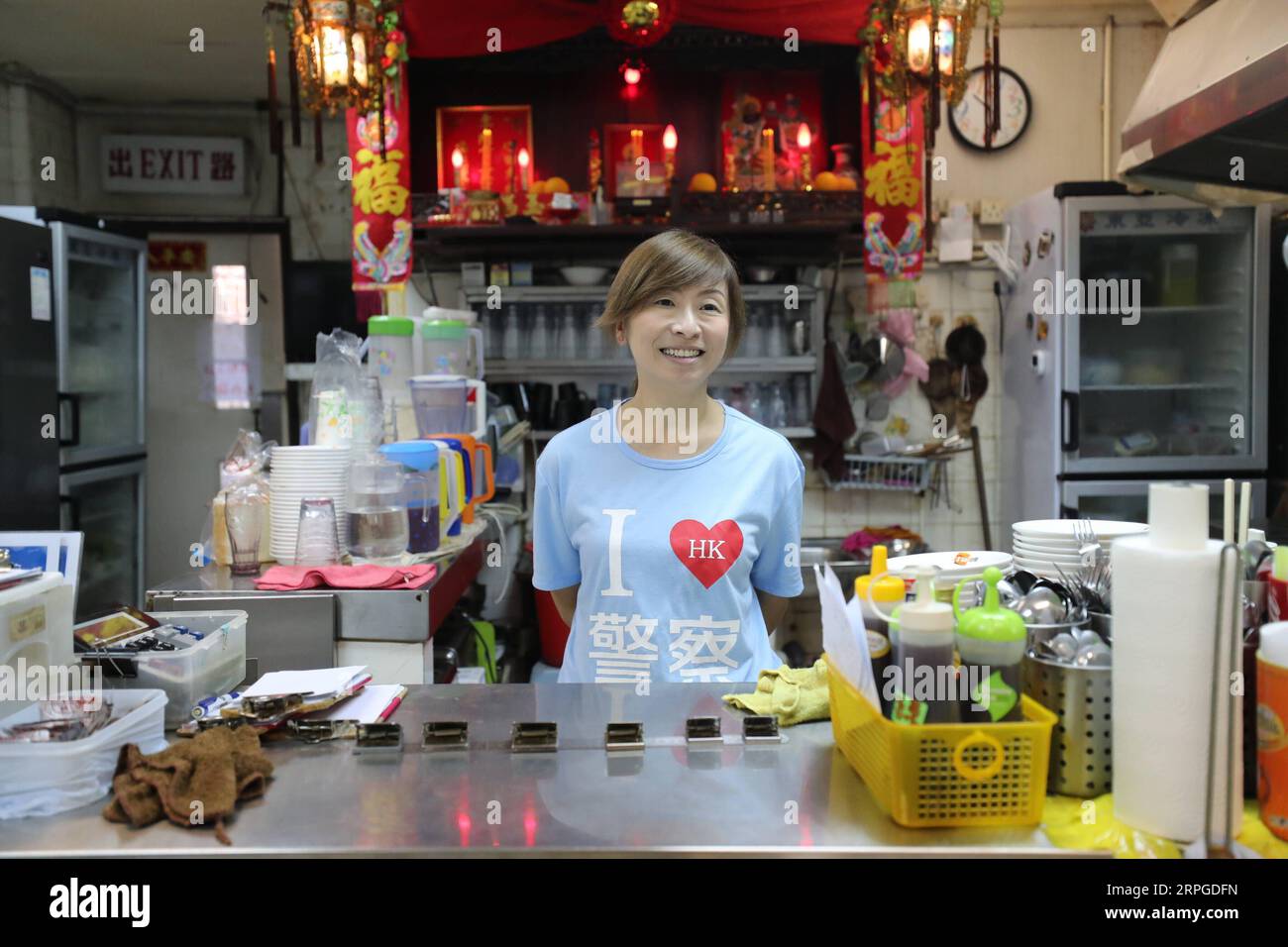 191012 -- HONG KONG, Oct. 12, 2019 -- Kate Lee, wearing a T-shirt with the I love HK police slogan on it, waits for customers at her tea restaurant in Kowloon, south China s Hong Kong, Oct. 10, 2019. Nestling in the labyrinthine seafood market of the quiet Lei Yue Mun fishing village in Hong Kong, a snug little tea restaurant has unexpectedly become a beacon of courage for ordinary Hong Kong people seeking peace amid the recent chaos. After she posted pictures backing up Hong Kong police against some radical protesters at the end of June, Kate Lee, the owner of the tea restaurant, found her co Stock Photo