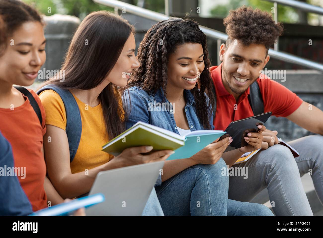 Diverse Multiethnic Students Reading Books And Using Digital Tablet Outdoors Stock Photo