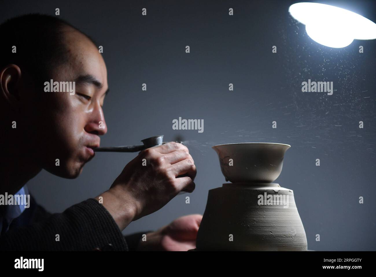 191016 -- NANCHANG, Oct. 16, 2019 -- A member of the team Kuaixueshiqing blows glaze to make porcelain works in Jingdezhen, east China s Jiangxi Province, Oct. 15, 2019. Egg shell porcelain, a renowned kind of traditional porcelain work produced in Jingdezhen of Jiangxi, is famous for its thin and transparent body which makes it special. Wang Minhui, 40, is head of the egg shell porcelain making team called Kuaixueshiqing . Wang and his two partners Du Xingyu and Liu Zhen, who take interest in porcelain, founded the team in 2010. The team, now having over 20 members, has insisted in striving f Stock Photo