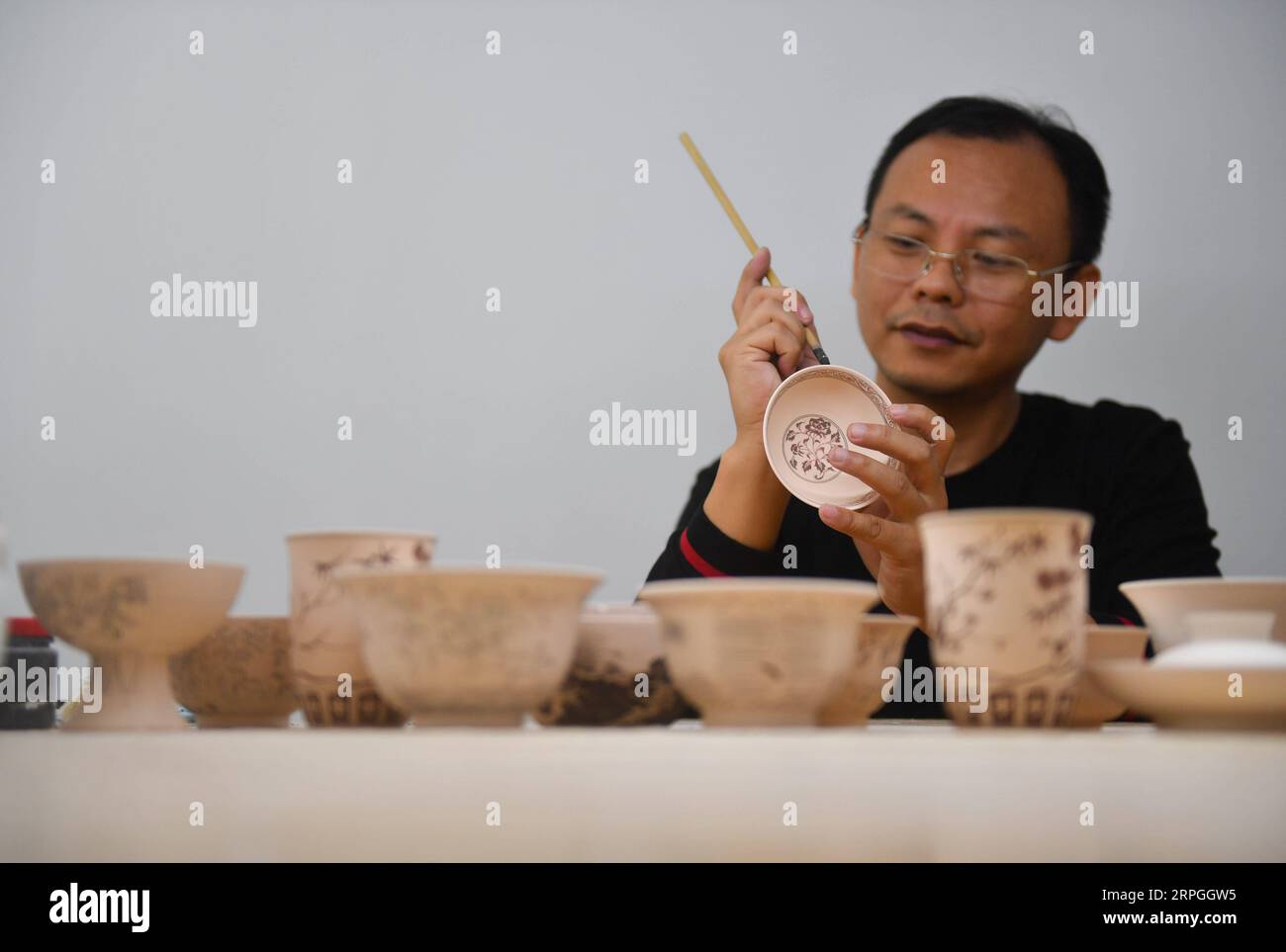 191016 -- NANCHANG, Oct. 16, 2019 -- A member of the team Kuaixueshiqing paints on a piece of porcelain work in Jingdezhen, east China s Jiangxi Province, Oct. 15, 2019. Egg shell porcelain, a renowned kind of traditional porcelain work produced in Jingdezhen of Jiangxi, is famous for its thin and transparent body which makes it special. Wang Minhui, 40, is head of the egg shell porcelain making team called Kuaixueshiqing . Wang and his two partners Du Xingyu and Liu Zhen, who take interest in porcelain, founded the team in 2010. The team, now having over 20 members, has insisted in striving f Stock Photo