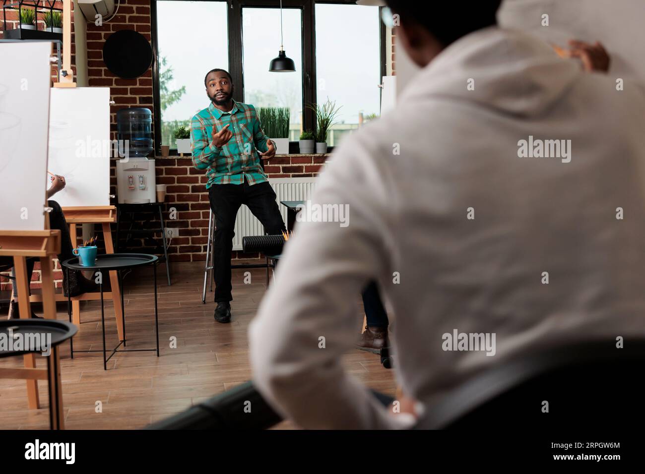 Young African American man teacher explaining pencil drawing techniques